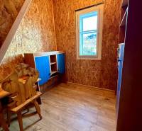 A room in a cabin with OSB boards and a wood-decor floor.