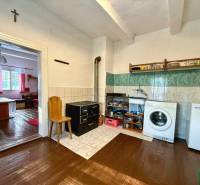 A cottage with a kitchen and living room, wooden decor flooring, white furniture, and an oven.