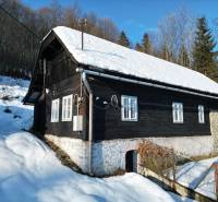 A cottage in Veľké Rovné surrounded by winter nature, snow-covered roof, wooden exterior.