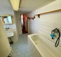 Bathroom in a cabin with white tiles and a bathtub, minimalist arrangement.