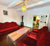 Living room in a cottage with a red sofa, chandelier, and wooden decor flooring.