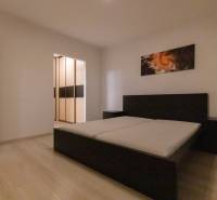 Bedroom in a 2-room apartment with a bed and a wardrobe, floor with wooden decor.