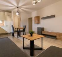 Living room in a two-room apartment with light furniture and a wooden decor floor.