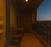 A night balcony with a view of the glowing city, chairs and a table for relaxation.