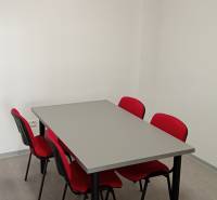 Four red chairs and a gray table in the office.