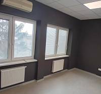 An office with windows, blinds, and air conditioning, equipped with a radiator and a floor with a wooden decor.