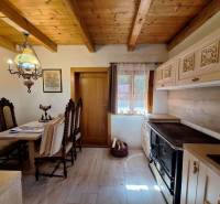 Rustic kitchen with wooden decor, decorative chairs, and a traditional stove in a cottage.