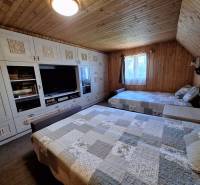 A cottage with a wooden decor floor, beds, wardrobes, and a window with a curtain.