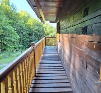 A wooden terrace at a cottage in Terchová on Vrátňanská Street, surrounded by the greenery of the forest.