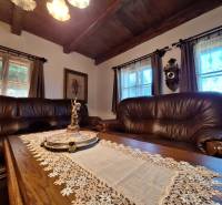 Wooden beams, leather sofas, decorative clock, and a statue in a cabin with a wooden decor floor.