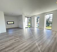 A spacious interior of a family house with a wooden decor floor and large windows.