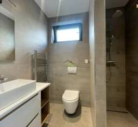 Bathroom in a family house with a sink, toilet, and shower, floor with wooden decor.