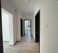 A hallway in a family house with a wooden decor floor and white walls.