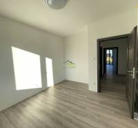 A room with a wooden decor floor in a family house. Light shines through the window.