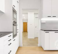 A kitchen in a 3-room apartment with white cabinets and a wood-patterned floor.