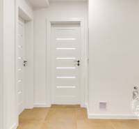 Hallway in a 3-room apartment with white doors and light flooring.