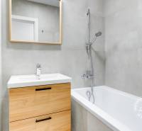 A bathroom with a bathtub, sink, and cabinet in a 3-room apartment with a wooden decor.