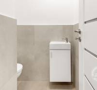 A bathroom in a 3-room apartment with a sink and toilet, light tiles.
