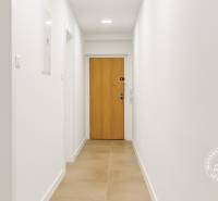 A bright hallway in a 3-room apartment with wooden doors and tiles.