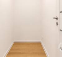 A small room with a wood-patterned floor and white walls in a three-room apartment.