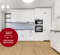 A bright kitchen with white cabinets and a wood-patterned floor in a three-room apartment.