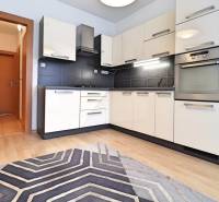 A kitchen unit with black tiles and a floor with a wooden decor in a 3-room apartment.