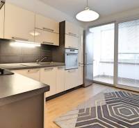 A kitchen in a 3-room apartment with a wooden decor floor and spacious windows.
