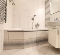 A bathroom with white tiles and a bathtub in a 3-room apartment.