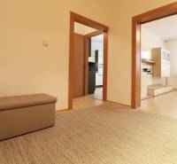 Hallway with a sofa, doors to the kitchen and living room, with a wooden-patterned floor.