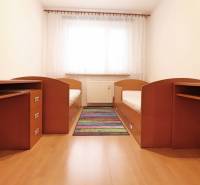 Children's room with two beds, desks, and a wooden decor floor.