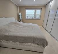 A bedroom in a family house with a large bed, a wardrobe, and white blinds.