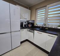 A kitchen in a family house with white cabinets, a black countertop, and cream-colored tiles.