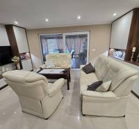 Open living room with cream seating, decorative candlesticks, and shelves in a family house.