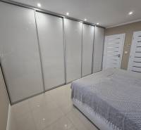 Bedroom in a family house with a large built-in wardrobe and tiled floor.