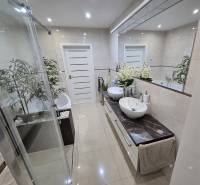 A bathroom in a family house with a modern shower and two sinks on a marble countertop.
