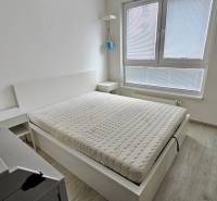 A bright bedroom with a bed and wood-decor flooring in a two-room apartment.