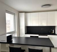 A kitchen in a 2-room apartment with white cabinets and a black countertop.