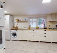 A kitchen in a family house with white furniture, a washing machine, and appliances.