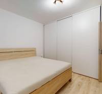 Bedroom with a bed, wardrobe, and wooden decor flooring in a family house.