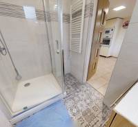A bathroom in a family house with a tiled floor and a shower corner.