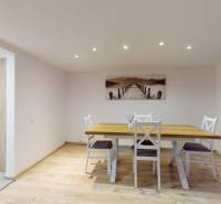 Dining area with a wooden table and chairs on a floor with wooden decor in a family house.