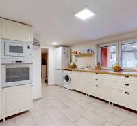 White kitchen with appliances and a window in a family house.
