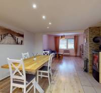 Dining room in a family house with a fireplace, elegant table, and wooden decor flooring.