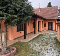 A family house in Dubovce with a tree in front of the entrance and a snow-covered lawn.