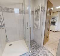 A bathroom with a glass shower enclosure and patterned tiles in a family house.