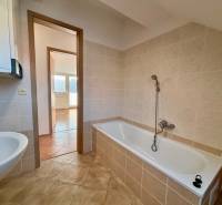 Bathroom with tiles next to a 2-room apartment, bathtub and sink, spacious layout.