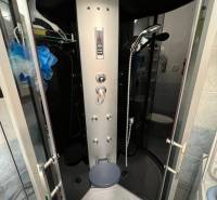Hydromassage shower cabin in a studio apartment with functional shower jets and storage space.