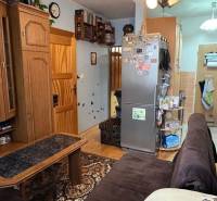 Living room with wood-patterned flooring, seating area, and kitchen.