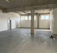 Commercial spaces with large windows and concrete flooring, neutral walls and a pillar.