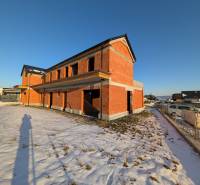 A family house in Mlynica during construction, surrounded by snow in a winter setting.